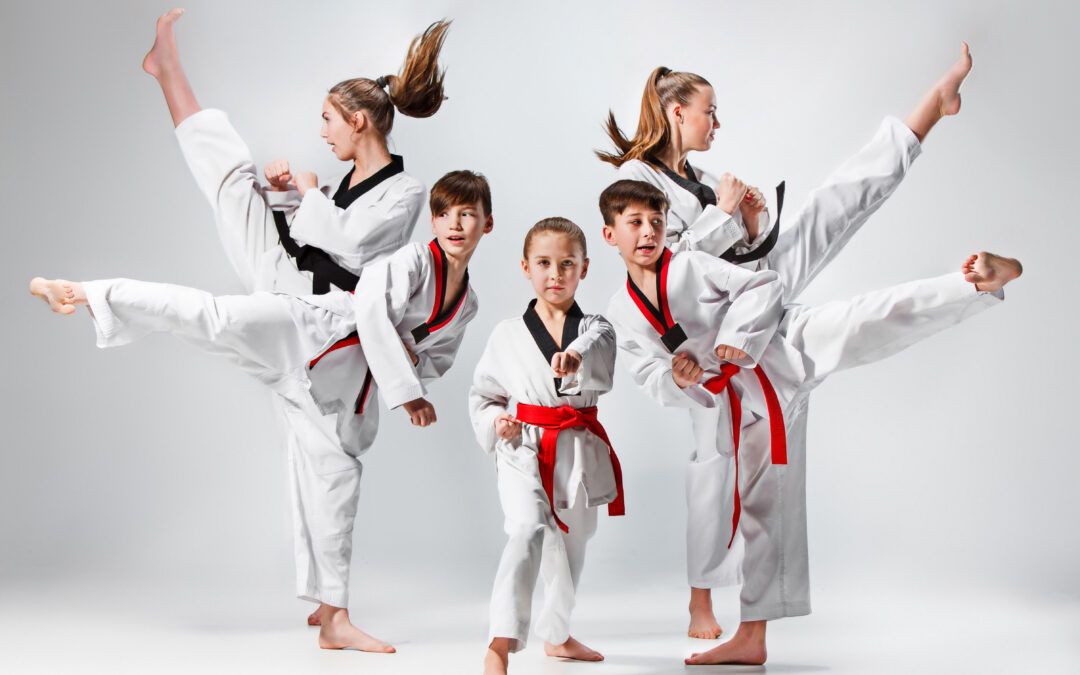 Niños en formación practicando patadas en una clase de taekwondo, combinando crecimiento personal y diversión.